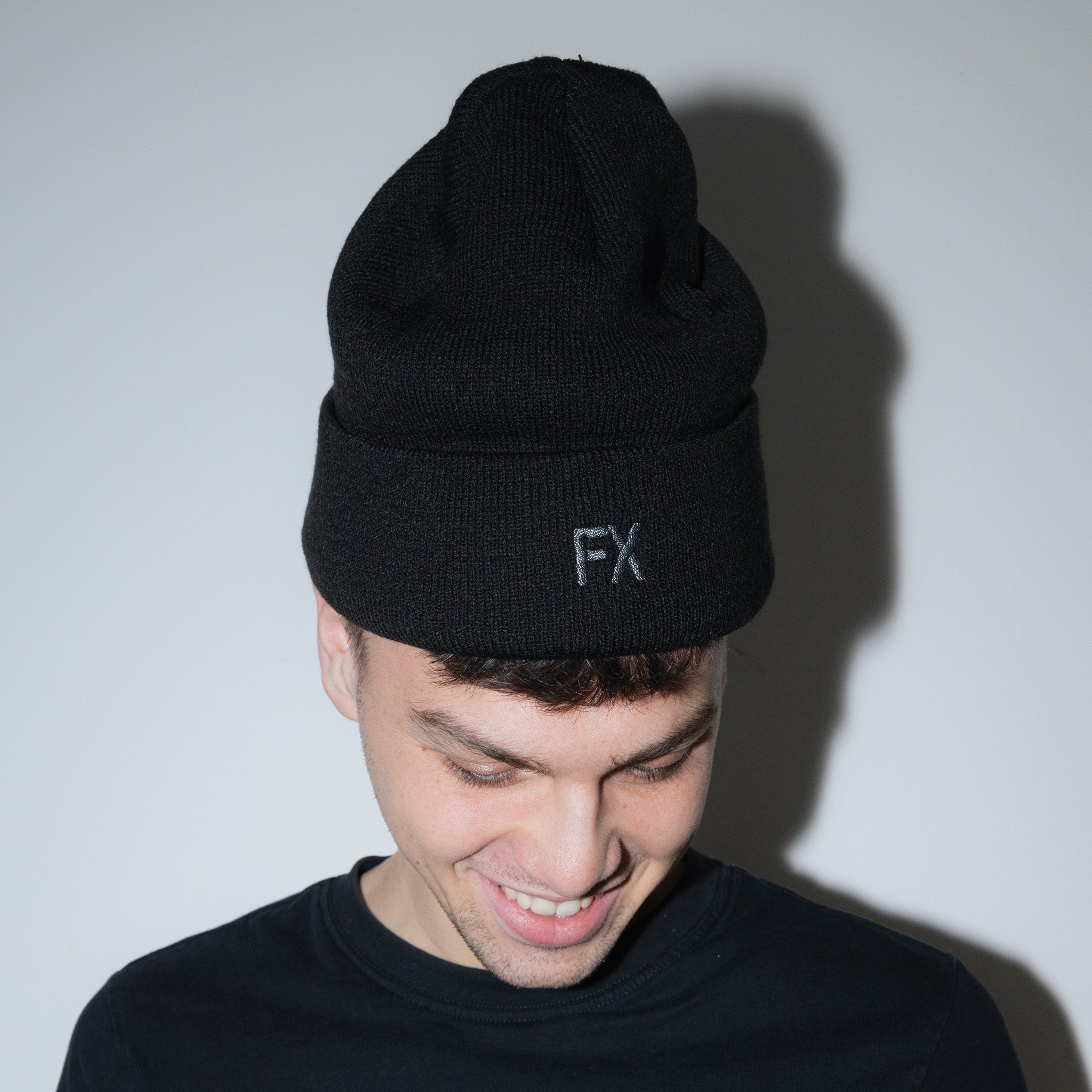 Eine Person trägt die Frankfurter Brauunion FX Beanie mit der FX-Stickerei auf der Vorderseite und ein schwarzes Hemd. Die mit Thinsulate gefütterte Mütze hebt sich von einem schlichten weißen Hintergrund mit einem sichtbaren Schatten ab.