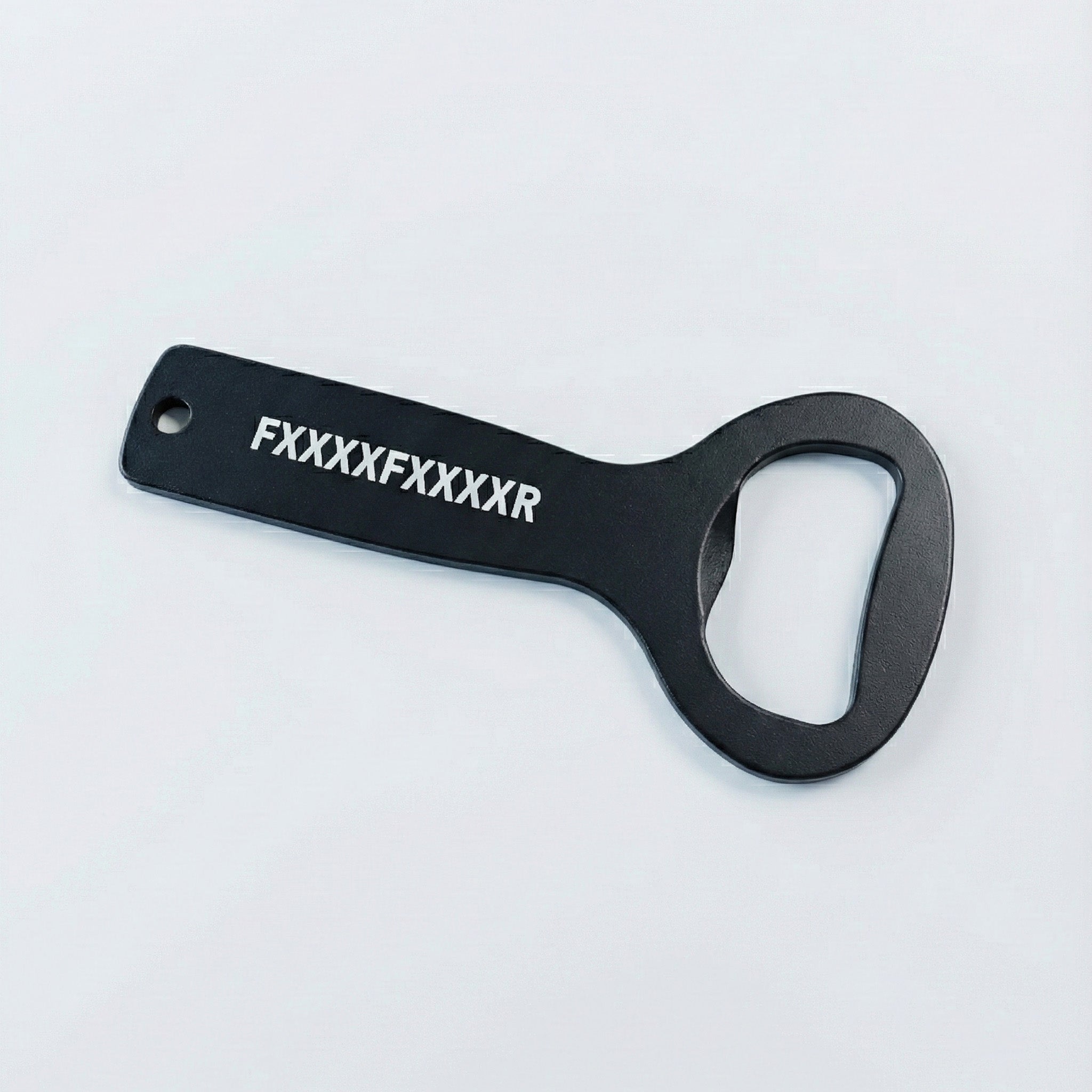 Ein FXXXXFXXXXR Flaschenöffner der Frankfurter Brauunion mit weißem Logo auf dem Griff liegt auf hellgrauer Fläche - praktisch am Schlüsselbund und ideal fürs nächste Bier.